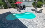 Pool deck with loungers, umbrella, & propane grill.